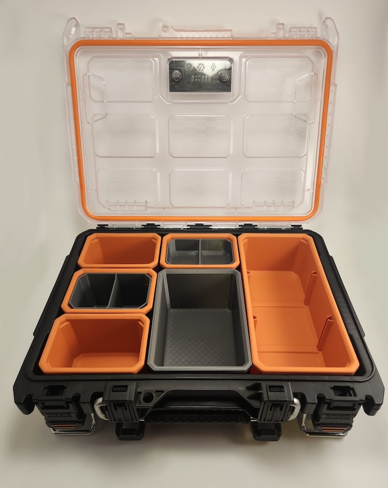 May include: A black and orange toolbox with a clear lid. The toolbox has multiple compartments for organising small items. The toolbox has a handle on the front.