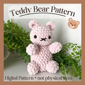 May include: A soft pink crocheted teddy bear with black eyes and a black stitched mouth. The image includes the text "Teddy Bear Pattern" and "Digital Pattern • not physical item". The bear is surrounded by green foliage.