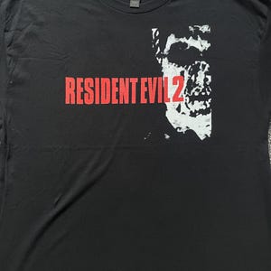May include: Black t-shirt with a red "RESIDENT EVIL 2" graphic and a white zombie face graphic.