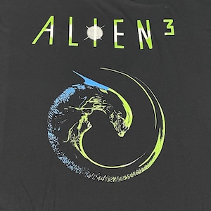 May include: Black t-shirt featuring a green and blue graphic of an alien creature from the film Alien 3. The text "ALIEN 3" is printed in green on the shirt.