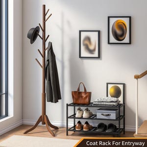 May include: A wooden coat rack with multiple branches for hanging coats and hats. A black hat and a dark gray coat hang on the rack. A black shoe rack with shoes, a handbag, and framed art are also visible.