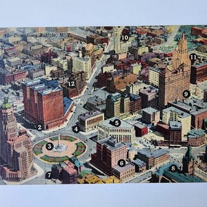 May include: Vintage postcard featuring an aerial view of Downtown Buffalo, N.Y. The image showcases numerous buildings, including skyscrapers and historical structures, with a central roundabout. The postcard is numbered 42.