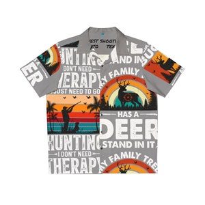 以下が含まれることがあります： 狩猟をテーマにしたグレーのボタンダウンシャツ。シャツには鹿のシルエット、ライフルを持ったハンター、そして「Hunting has a deer stand in it. I don't need therapy, my family tree has a deer stand in it.」というテキストが書かれています。