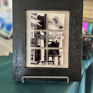 May include: Black and white photo collage in a black frame with a silver stand. The photo shows a street scene with signs that read "King St" and "Market St" and a "One Way" sign.