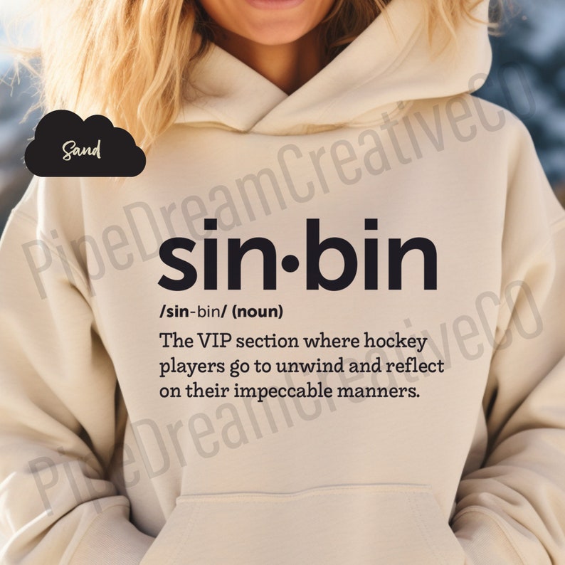 K&ouml;nnte beinhalten: Ein beiger Hoodie mit dem Text "sin-bin" in Schwarz, definiert als "Der VIP-Bereich, in dem Hockeyspieler entspannen und &uuml;ber ihr tadelloses Benehmen nachdenken."
