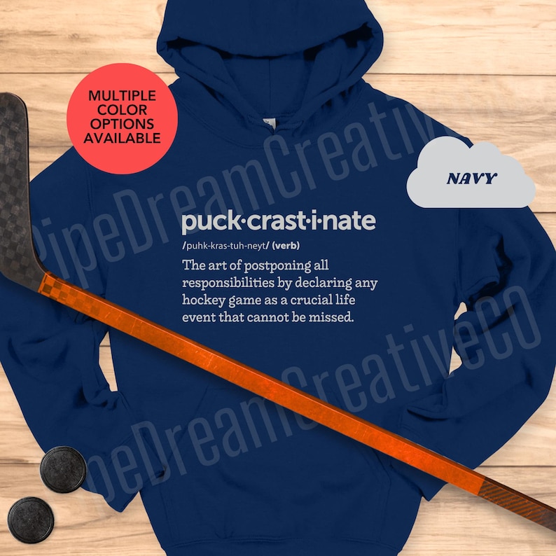 May include: Navy blue hoodie with a white graphic that says "puck-crast-i-nate" and defines the word as "The art of postponing all responsibilities by declaring any hockey game as a crucial life event that cannot be missed."