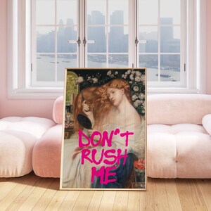K&ouml;nnte beinhalten: Ein gerahmter Druck eines Gem&auml;ldes, das eine Frau mit langen roten Haaren zeigt, die in einen Spiegel schaut. Das Gem&auml;lde ist von Blumen umgeben und der Text "DON'T RUSH ME" ist in rosa Buchstaben auf dem Gem&auml;lde geschrieben.