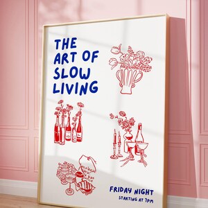 May include: A framed art print with a white background and red and blue illustrations. The text "THE ART OF SLOW LIVING" is in blue. Red illustrations include flowers, bottles, and glassware. The phrase "FRIDAY NIGHT STARTING AT 7PM" is also in blue.