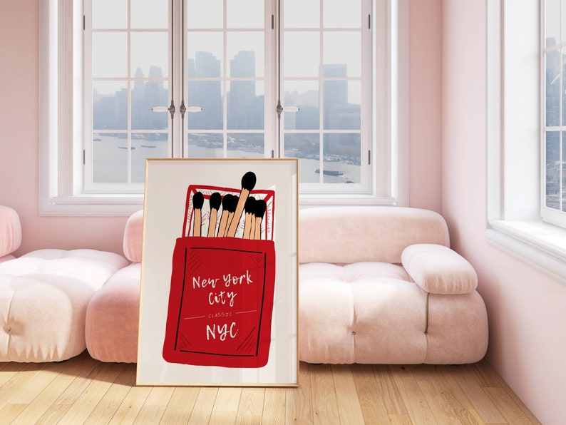 May include: A framed print of a red matchbox with the text "New York City Classic NYC" and black and brown matches inside.