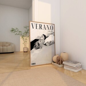 May include: A framed black and white photograph of a couple lying on a beach. The magazine cover reads "VERANO a vintage summer".