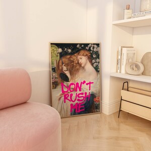 K&ouml;nnte beinhalten: Ein gerahmter Druck eines Gem&auml;ldes, das eine Frau mit langen roten Haaren zeigt, die in einen Spiegel schaut. Das Gem&auml;lde ist mit dem Text "DON'T RUSH ME" in Pink &uuml;berlagert.