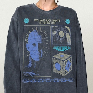 Op de afbeelding: Donkergrijs shirt met lange mouwen met een grafisch ontwerp. Het ontwerp bevat een blauwe afbeelding van een personage, een puzzelbox en de tekst "WE HAVE SUCH SIGHTS TO SHOW YOU". Het shirt heeft een vintage uitstraling.