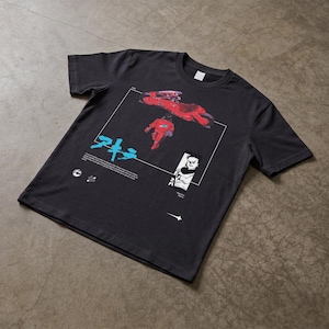 May include: Dark gray t-shirt featuring a graphic from the anime Akira. The design includes a red motorcycle and figure, Japanese text, and a black and white illustration. The shirt is made of a soft material.