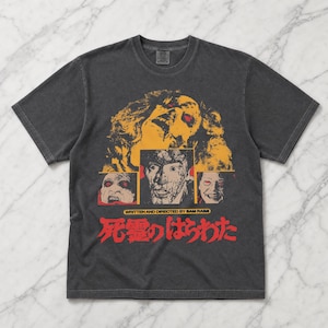 May include: Dark grey t-shirt with a horror movie graphic. The design features a central monster image with red eyes, surrounded by other horror-themed images. Text in English and Japanese is also present.