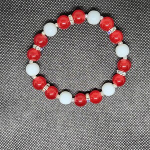 May include: A red and white beaded bracelet with clear rhinestones on the red beads.
