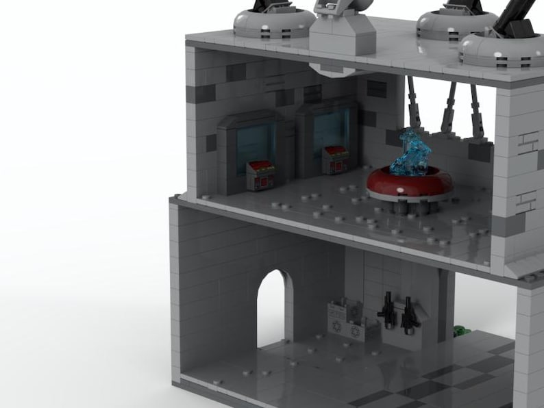 K&ouml;nnte beinhalten: Ein zweist&ouml;ckiges graues Lego-Geb&auml;ude mit einem blauen und roten Raumschiff im Inneren. Das Geb&auml;ude hat ein graues Dach mit einer schwarzen Antenne und eine graue T&uuml;r im Erdgeschoss.