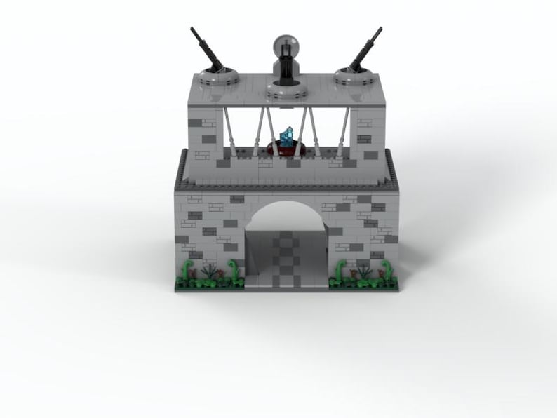 K&ouml;nnte beinhalten: Ein graues Lego-Modell eines Burgtores mit drei Kanonen oben und gr&uuml;nen B&uuml;schen auf beiden Seiten.