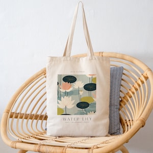 May include: A white canvas tote bag with a graphic of water lilies and the text "JULY FLOWER WATER LILY PURITY - ENLIGHTENMENT - BEAUTY".