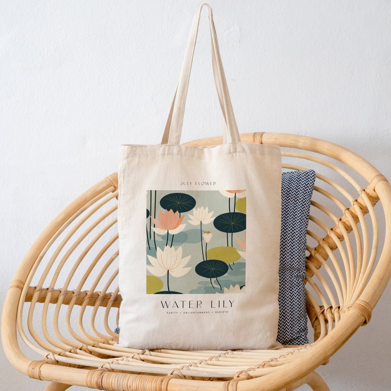 May include: A white canvas tote bag with a graphic of water lilies and the text "JULY FLOWER WATER LILY PURITY - ENLIGHTENMENT - BEAUTY".