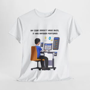 Pode incluir: Camiseta branca com um gráfico de uma pessoa sentada em frente a um computador com o texto "My code doesn't have bugs, it has random features".
