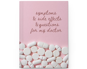 May include: A pink notebook with the text "symptoms & side effects & questions for my doctor" in brown cursive writing. The bottom of the notebook is covered with white pills.