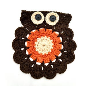 May include: A handmade crochet owl coaster in shades of brown, orange, and cream. The owl features button eyes and a scalloped edge, creating a whimsical and decorative item. This coaster is perfect for adding a touch of handmade charm to any space.