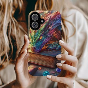 May include: A colorful phone case with a dragon design. The dragon is green, blue, and purple with red accents. The dragon is perched on top of a book with gems scattered around it.