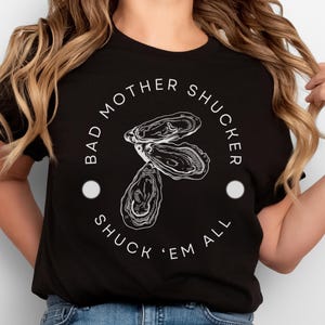 May include: Black t-shirt with white text that reads "Bad Mother Shucker Shuck 'Em All" and a graphic of an oyster.