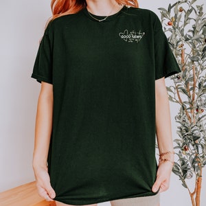 May include: A black t-shirt with a white graphic design that says "GOOD NEWS" with a heart and arrow design.