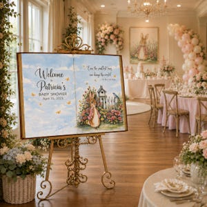 May include: A large open book-shaped sign on a gold metal easel. The left page reads Welcome to Patricia's BABY SHOWER April 25, 2026. The right page features a rabbit illustration, a birdhouse, and the text Even the smallest ones can change the world.