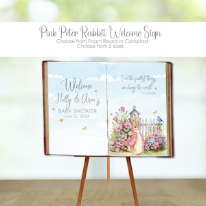 May include: A pink Peter Rabbit welcome sign for a baby shower. The sign features the text "Welcome to Holly & Aron's BABY SHOWER June 22, 2024". The right side of the sign has a watercolor illustration of Peter Rabbit.