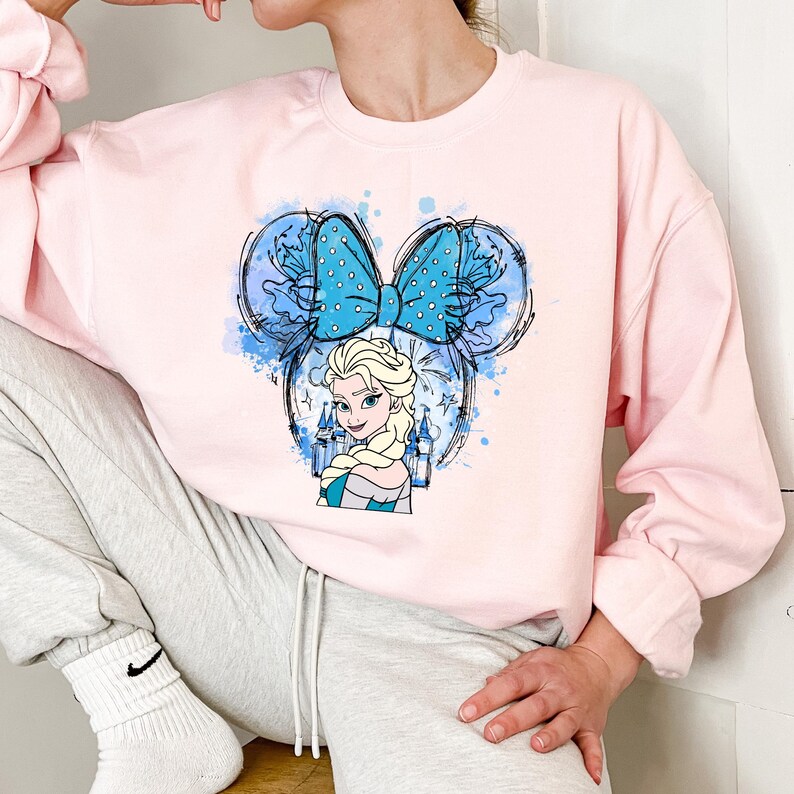 a woman sitting on a chair wearing a pink sweatshirt