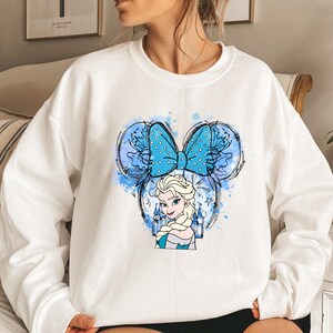 a woman wearing a white sweatshirt with a blue bow on her head