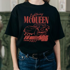 a woman wearing a black t - shirt with a picture of a car on it