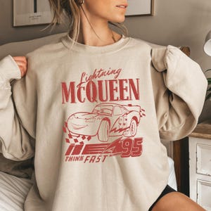 a woman is sitting on a bed wearing a sweatshirt