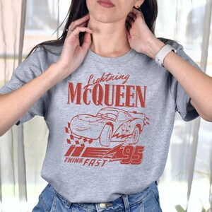 a woman wearing a gray t - shirt with a picture of a car on it