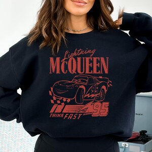a woman wearing a black sweatshirt with a picture of a car on it