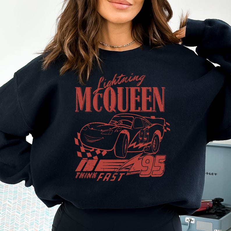 a woman wearing a black sweatshirt with a picture of a car on it