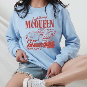 a woman sitting on a stool wearing a blue sweatshirt