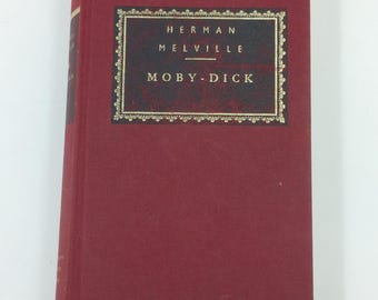 May include: A red hardcover book with a gold-trimmed title page. The title page reads "Herman Melville" and "Moby-Dick".