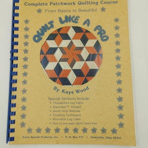 May include: A book titled "Quilt Like a Pro: Complete Patchwork Quilting Course" by Kaye Wood. The cover features a colourful quilt design with a starburst pattern. The book includes special sections on Thunderbird Log Cabin, Starmaker Designs, Quick Strip Methods, Finishing Techniques, Reversible Log Cabin, and how to pre-wash fabric to prevent fraying.