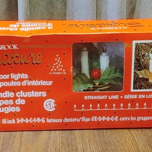 May include: An orange Alderbrook Signature box of indoor lights. The box features a window showing candle clusters and the text "16 indoor lights" and "4 candle clusters". The box has a picture of candles.