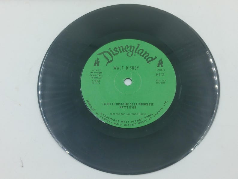 May include: A vintage black vinyl record with a green label featuring the Disneyland logo and "Walt Disney" text. The label also includes French text: "LA BELLE HISTOIRE DE LA PRINCESSE NATT&Eacute; D'OR".