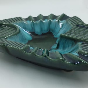 May include: A green and blue ceramic ashtray with a fluted edge and a textured design. The ashtray has three compartments.
