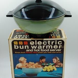 May include: A vintage green and black electric bun warmer and hot food server in its original box. The box has the text "pop electric bun warmer and hot food server" and "Keeps food PIPING HOT while you cook and serve".