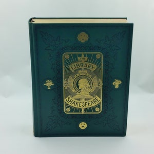 May include: A green hardback book with gold lettering and illustrations. The title is "The Library of Shakespeare".