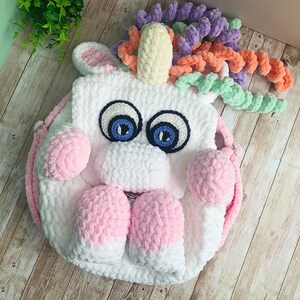Sac à dos licorne fait main au crochet - Sac en peluche blanc avec pattes et bretelles roses, cheveux bouclés pastel, sac à dos pour tout-petit animal