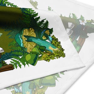 This is a close-up image of the bandana scarf folded over. It shows the pattern that includes green mushrooms, ferns, twigs, and mosses. The color palette is greens, turquoise blue, white, and a bit of brown.