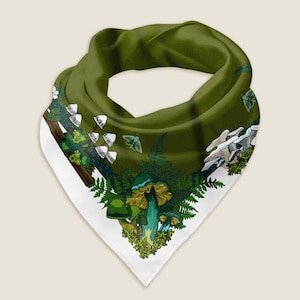 The green mushroom bandana styled as a wrap shows the details of the hand-drawn artwork, which includes a variety of green and yellow mushrooms, moths, ferns, and moss illustrated around a green middle with a white border. Behind the scarf is a green background with illustrated pine trees and the Wander Wrap logo.