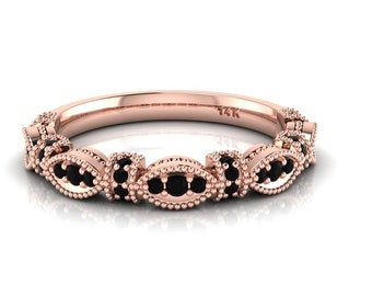 Op de afbeelding: Een roségouden bandring met een delicaat ontwerp met zwarte edelstenen die in een gegolfd patroon zijn gezet. De ring is gemarkeerd met "14K".